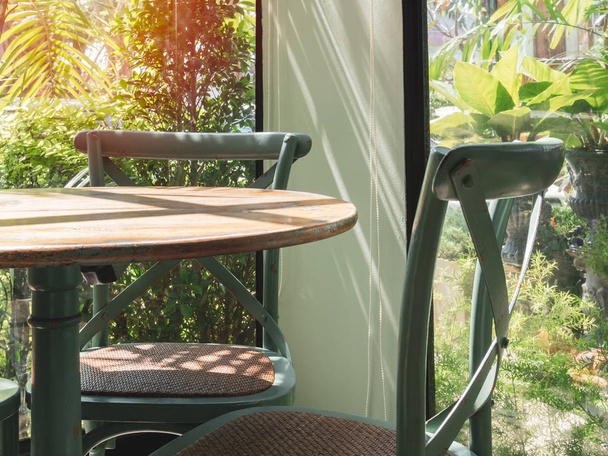 Mesa y silla de madera vintage en habitación de cristal cerca del jardín
 - Foto, imagen