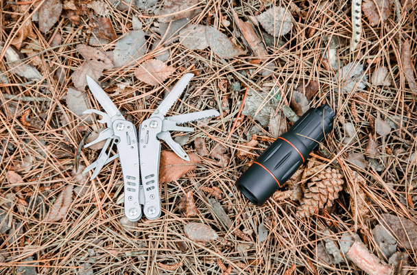 松の葉で覆われて地面にモノクルとマルチ ツール ナイフ - 写真・画像