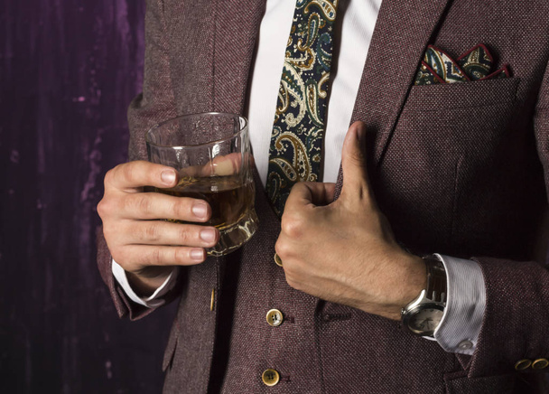 business man with whiskey in his hand shows a hand sign that everything is in order - Foto, imagen