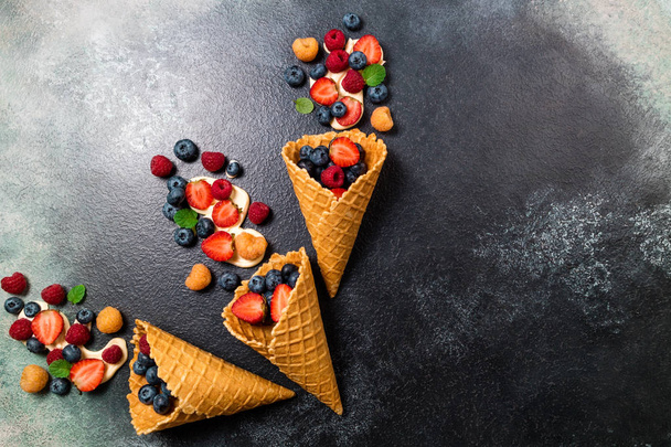 Fresh berries and cream in ice cream cone. Strawberry, raspberry - Фото, зображення