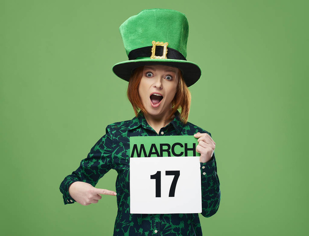 Кричащая женщина в шляпе лепрекона указывает на календарь
  - Фото, изображение