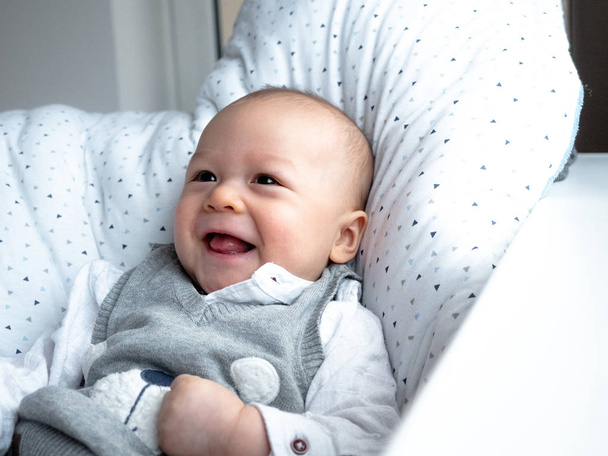 Bonito 4 meses de idade misto meia raça asiático caucasiano menino olhando feliz sorrindo e rindo da câmera, menino saudável criança. Meio tailandês meio polaco. Inverno, pano de elegância sentado ao lado da janela
 - Foto, Imagem