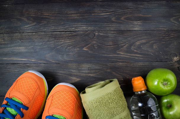 Sport shoes, apple, bottle of water and towel on wooden backgrou - Photo, Image