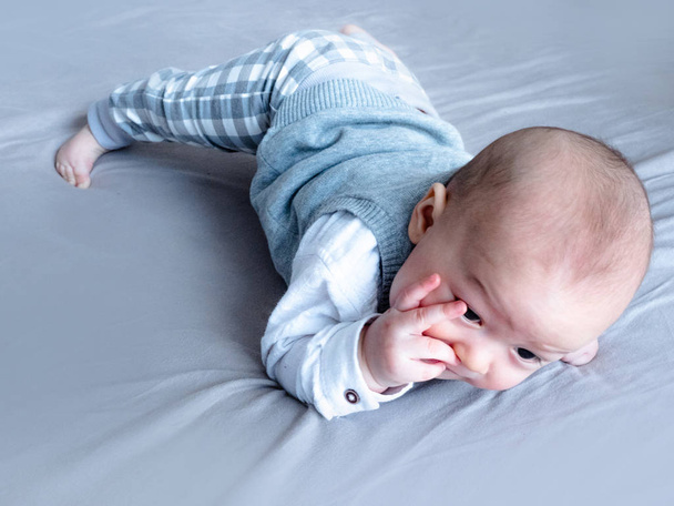 Bebé lactante Chupando dedos, pequeño retrato del bebé acostado en la cama con el pulgar en la boca. lindo 4 meses viejo mixto medio raza asiático caucásico chico
 - Foto, imagen