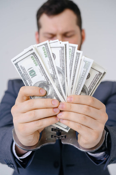 Businessman in handcuffed hold dollar bribe - Фото, изображение