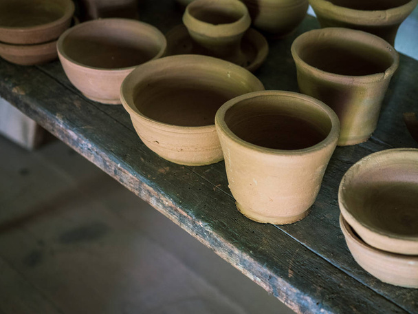 Ceramic handcraft pottery, Craftsman artist making craft, pottery, Shelves in pottery workshop full of hand crafted dishes and pots made of clay ready for glazing. - Fotó, kép