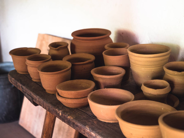 Keramische ambachtelijke aardewerk, vakman kunstenaar maken van ambachtelijke, pottenbakkerij, planken in Pottery workshop vol met de hand vervaardigde gerechten en potten gemaakt van klei klaar voor beglazing. - Foto, afbeelding