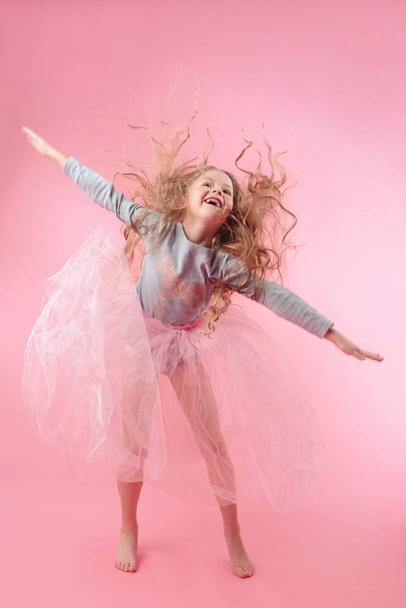 linda niña divertida con el pelo largo y rubio saltando sobre fondo rosa
 - Foto, Imagen