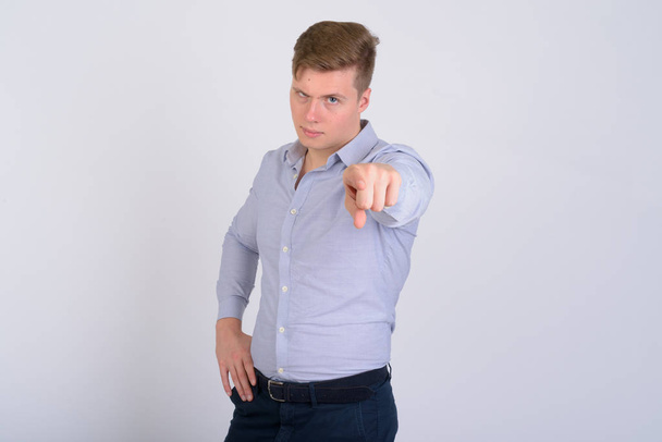 Portret van jonge boos blonde zakenman wijzend op camera - Foto, afbeelding