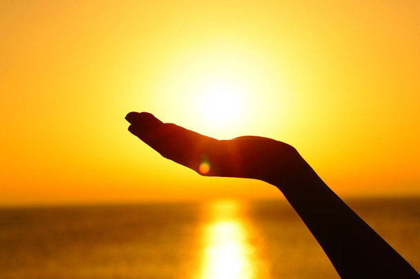 Woman hand holding sun at sunset on the beach - Photo, Image