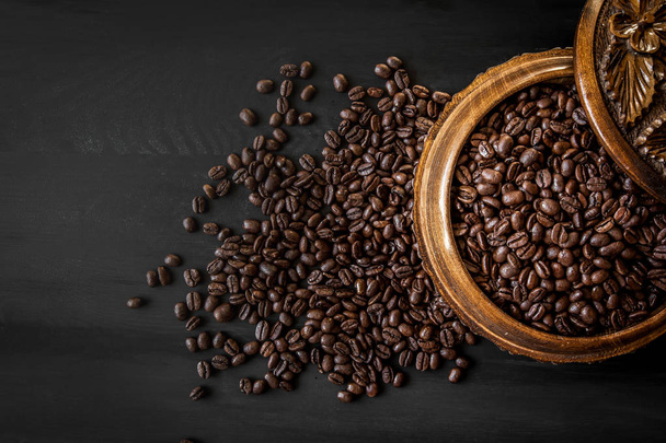 Fresh roasted arabica and robusta coffee beans. Coffee in a wooden bowl on a dark wood background - Photo, Image