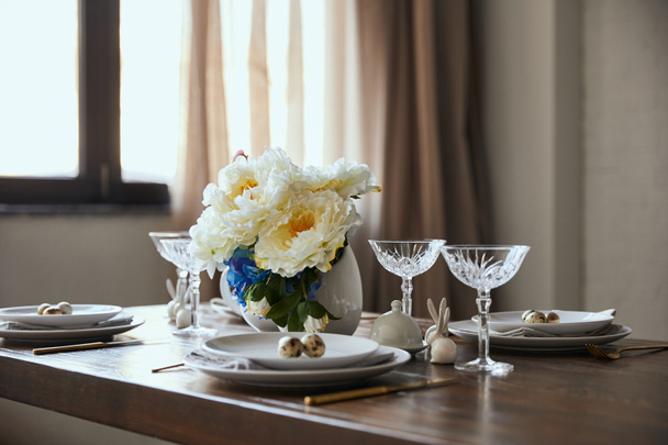 перепелиные яйца на белых тарелках, цветы в вазе и хрустальные бокалы на деревянном столе дома
 - Фото, изображение