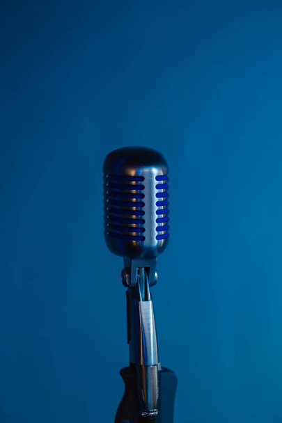 Retro microphone against dim blue light restaurant background. - 写真・画像