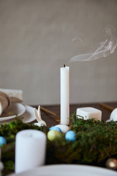 селективный фокус свечи и тарелок возле мха на деревянном столе в домашних условиях
 - Фото, изображение