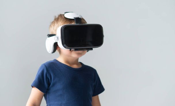 Retrato de menino feliz em um fone de ouvido de realidade virtual. Criança atraente usando óculos de proteção em casa. Tecnologia de entretenimento e conceito de geração Z
. - Foto, Imagem