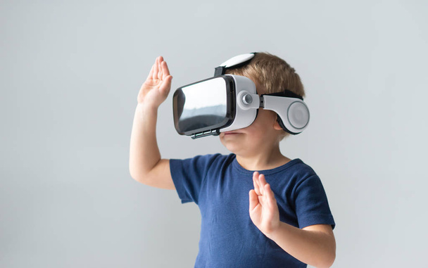 Portrait of happy boy in a virtual reality headset. Attractive kid using vr goggles at home. Entertainment technology and generation Z concept. - Fotó, kép
