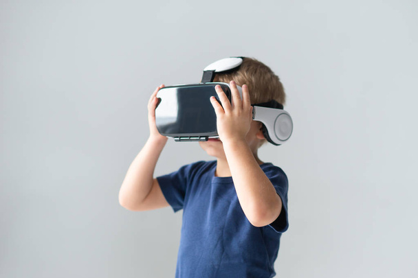 Portrait of happy boy in a virtual reality headset. Attractive kid using vr goggles at home. Entertainment technology and generation Z concept. - Fotoğraf, Görsel