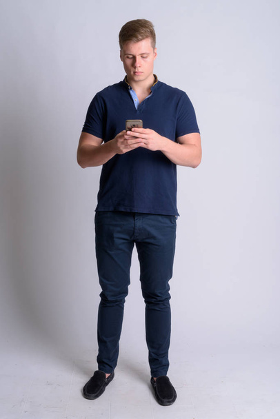 Full body shot of young blonde handsome man using phone - Photo, Image