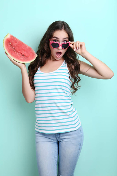 Beautiful woman in sunglasses holding watermelon on mint background - Photo, Image
