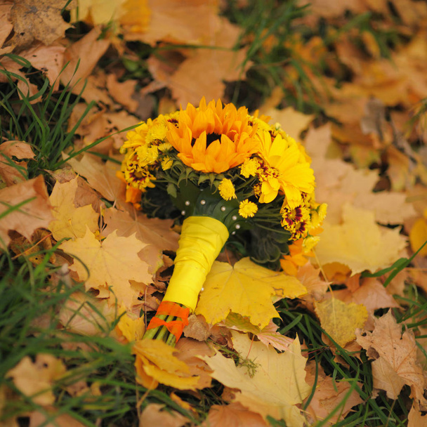 Wedding bouquet with yellow flowers on fallen autumn leaves - 写真・画像
