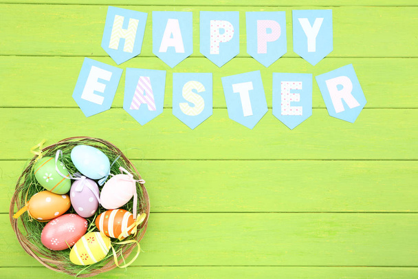 Texto Feliz Pascua con huevos de Pascua en la mesa de madera verde
 - Foto, Imagen