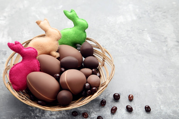 Chocolate easter eggs with fabric rabbits on grey wooden table - Foto, Imagem