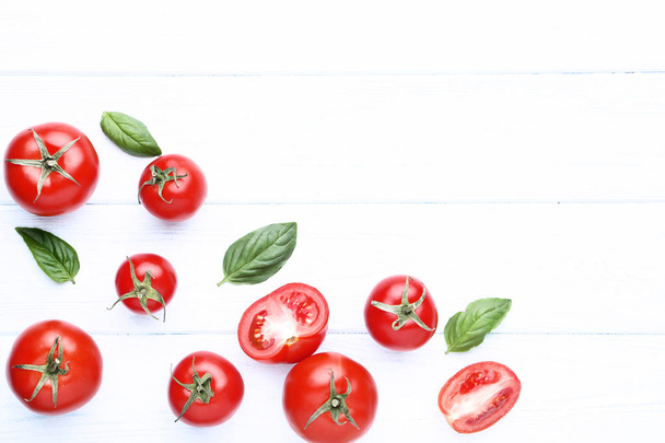 Fresh and ripe tomatoes with basil leafs on wooden table - Foto, Bild
