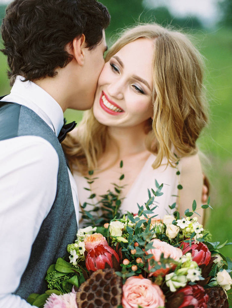 outdoor portrait of happy newlyweds, smiling bride holding beautiful bouquet  - Fotoğraf, Görsel