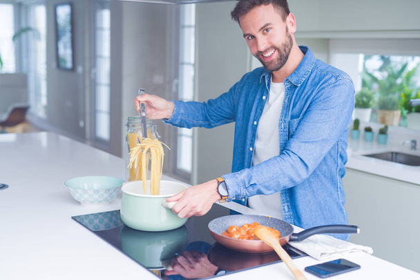 Hombre guapo cocinando pasta en casa - Foto, Imagen
