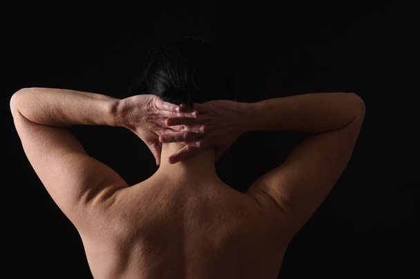 middle-aged woman with pain in the neck on black background - Photo, Image