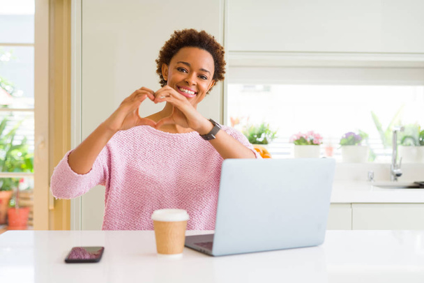 Young african american woman working using computer laptop smiling in love showing heart symbol and shape with hands. Romantic concept. - Photo, image