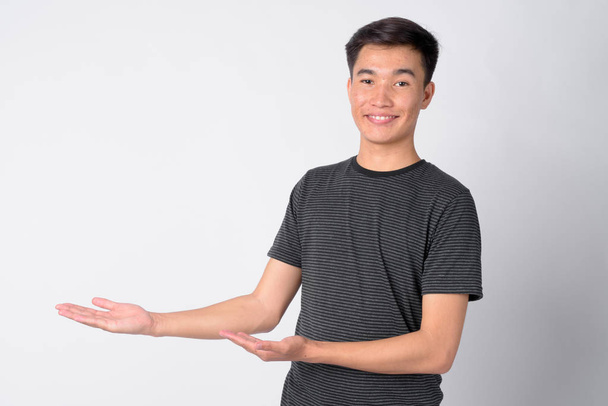 Porträt eines jungen glücklichen asiatischen Mannes, der etwas zeigt - Foto, Bild