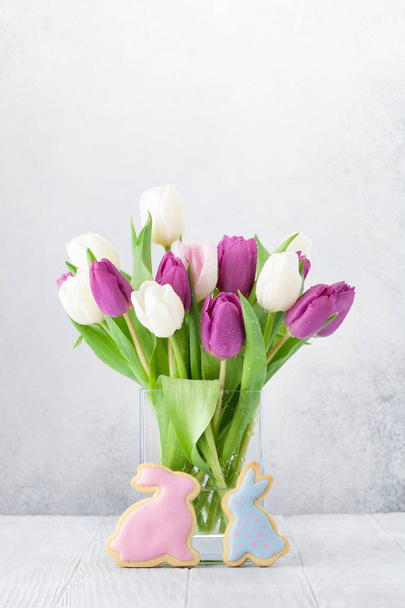 Cartão de Páscoa com flores de tulipa buquê e biscoitos de coelho na frente da parede de pedra
  - Foto, Imagem
