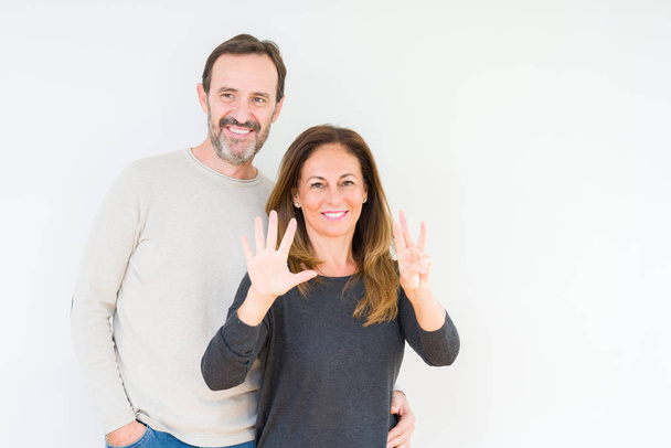 Kaunis keski-ikäinen pari rakastunut eristetty tausta osoittaa ja osoittaa sormilla numero kahdeksan hymyillen itsevarma ja onnellinen
. - Valokuva, kuva