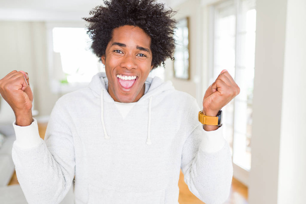 African American man wearing sweatshirt celebrating surprised and amazed for success with arms raised and open eyes. Winner concept. - Photo, Image