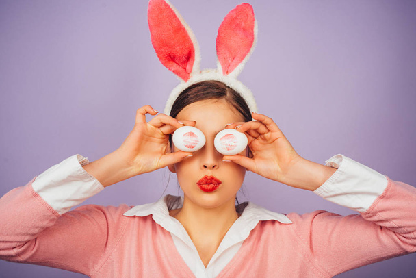 Happy easter. Young woman in rabbit bunny ears. Lipstick kiss print on easter egg. - 写真・画像