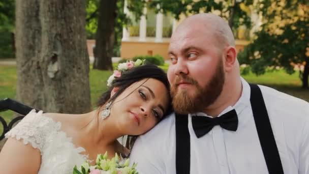 Happy newlyweds are sitting on a bench in the park. - Footage, Video
