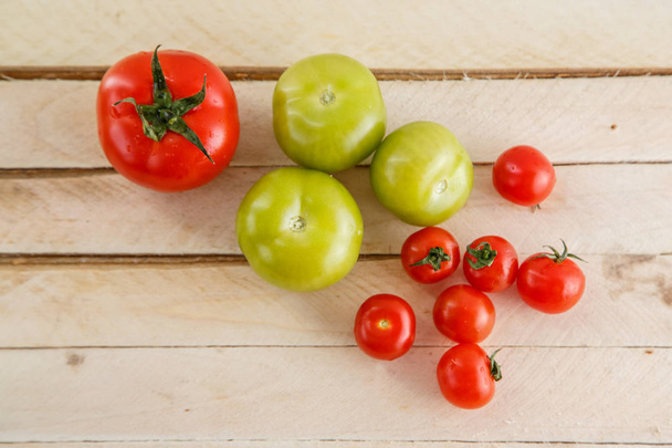 different varieties of tomatoes on a wooden background. - Фото, зображення