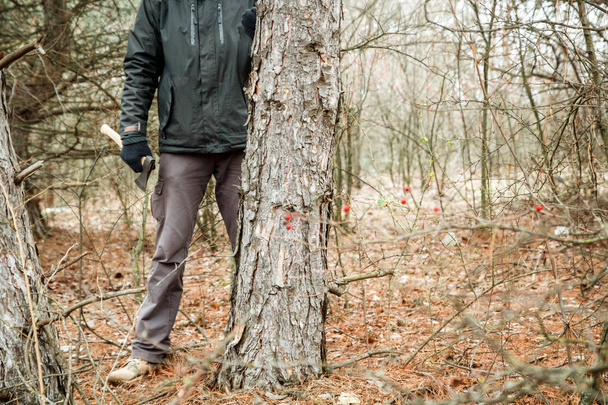 ο άνθρωπος που κρύβεται στο δάσος το φθινόπωρο με ένα τσεκούρι - Φωτογραφία, εικόνα