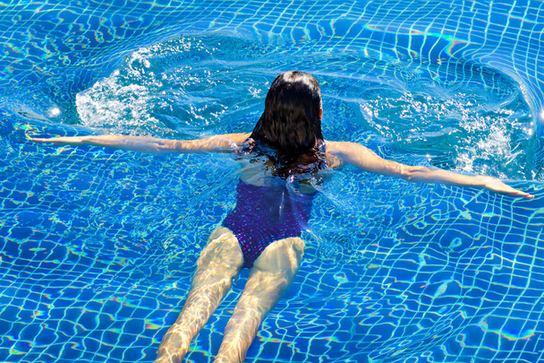 Вид зверху на жінку, що плаває в басейні. Широкі відкриті руки на блакитній чистій воді
.  - Фото, зображення
