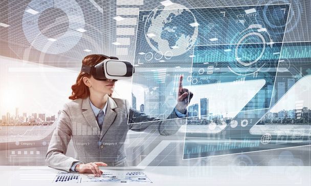Concept of modern technologies for up to date business needs. Successful business woman in suit using virtual reality goggles and digital media interface. - Foto, imagen