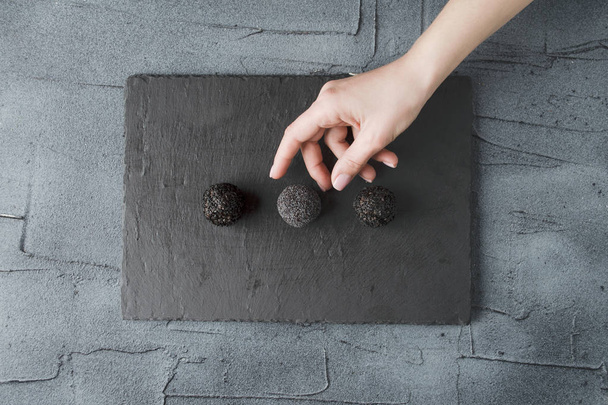 minimalista természetes nyers édességek a fekete kő ellátás a kezét szedés egy cukorka - Fotó, kép