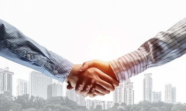Près des gens d'affaires serrant la main comme symbole du partenariat. Techniques mixtes
 - Photo, image