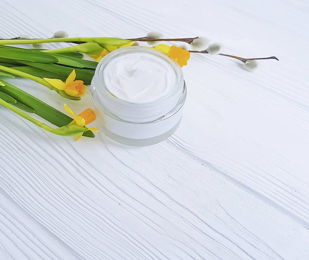 cosmetic cream, flower narcissus, on a white wooden background willow fluffy - Valokuva, kuva