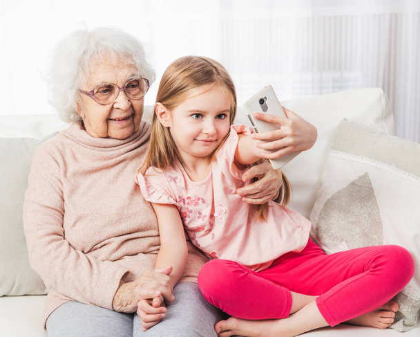 Granddaughter taking selfie with great-grandmother - Fotoğraf, Görsel
