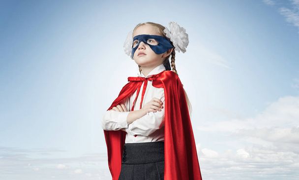 Маленька впевнена дитина в масці і мисі грає крутого супергероя
 - Фото, зображення