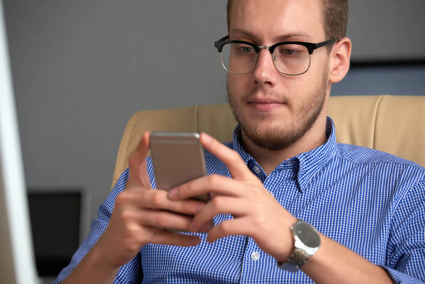 Handsome young businessman reading messages in his smartphone - Foto, Imagen