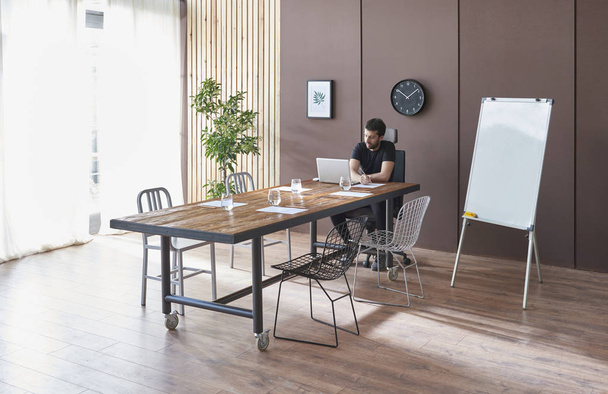 Pared marrón y fondo de madera, mesa de madera, sala de oficina con planta de silla y tabla. El hombre está trabajando. - Foto, imagen