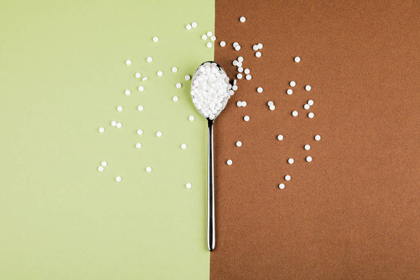 Comprimidos substitutos do açúcar com uma colher sobre um fundo verde-castanho
 - Foto, Imagem