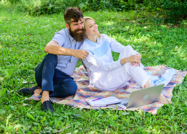 Couple bearded man and blonde woman relax nature while sit on green grass meadow. Relax and inspiration concept. Family enjoy relax nature background. Couple with laptop relax natural environment - Фото, изображение